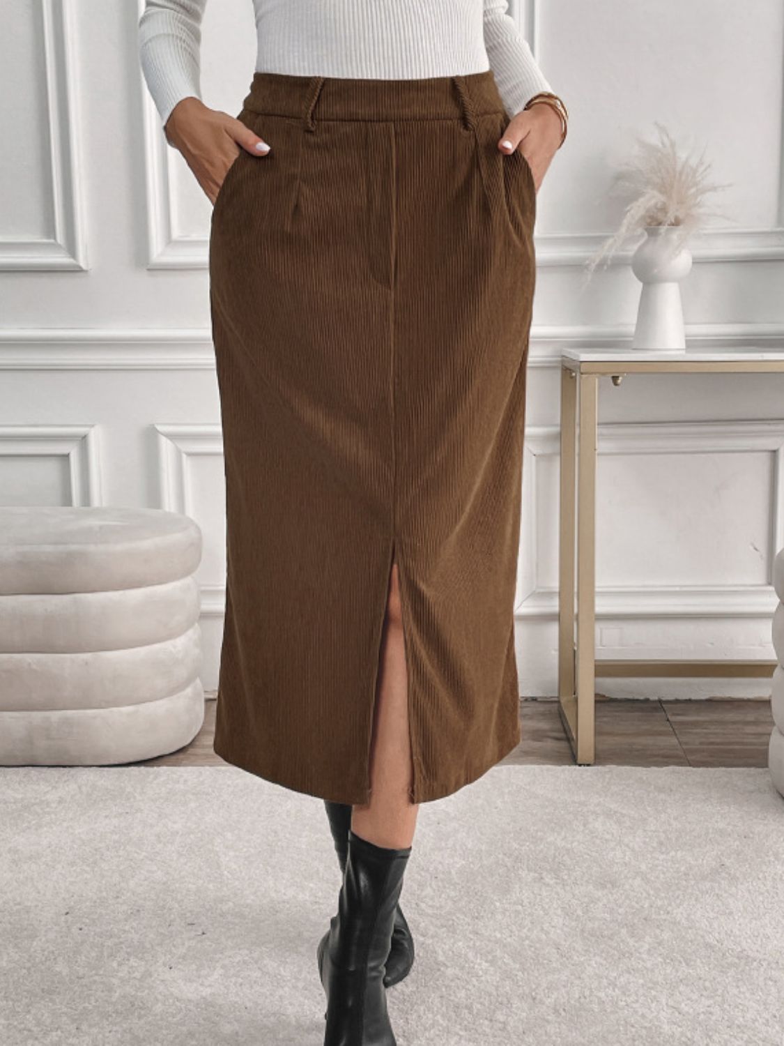 Brown corduroy midi skirt with a front slit and pockets, styled with black boots.