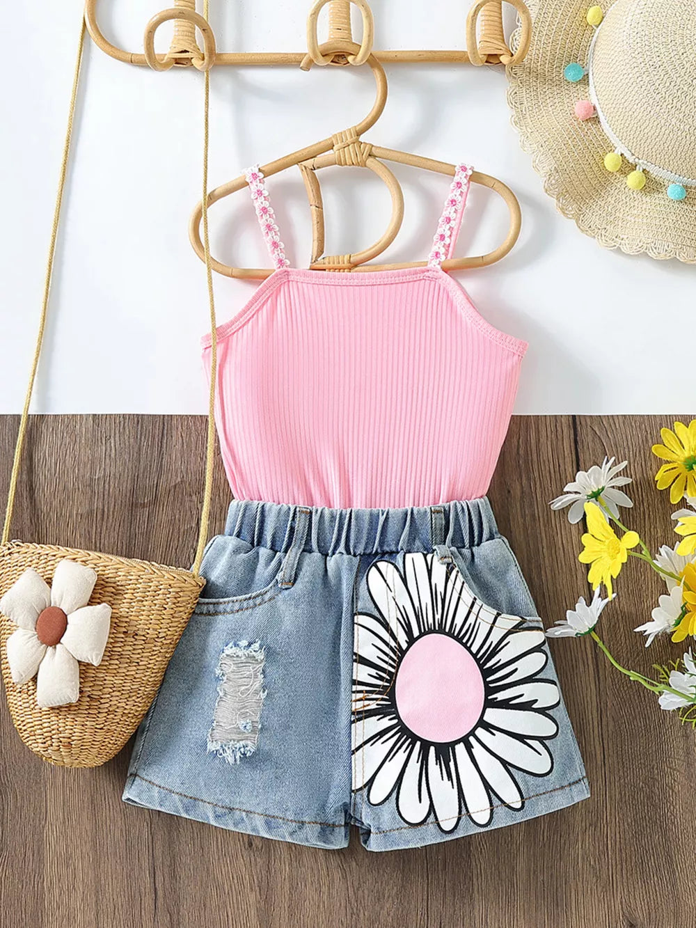Pink ribbed cami with floral straps and distressed denim shorts with daisy print.