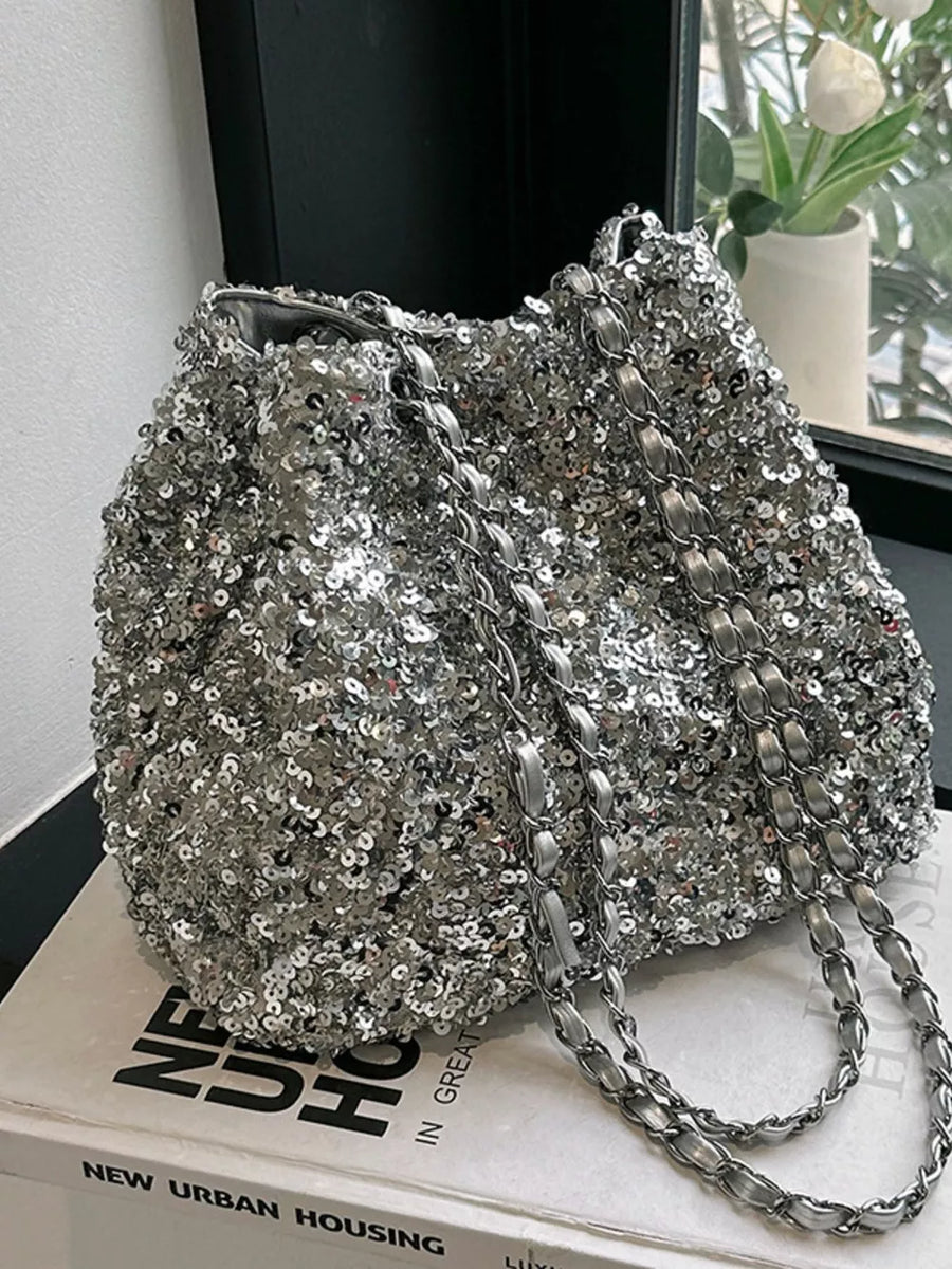 Dazzling sequin bucket shoulder bag in silver with a chic chain strap.