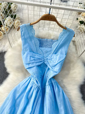 Blue eyelet maxi dress with square neckline, smocked bodice, cutout detail and bow accent.