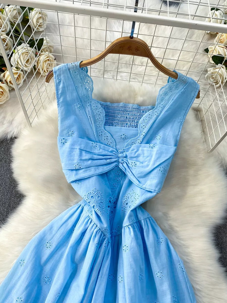 Blue eyelet maxi dress with square neckline, smocked bodice, cutout detail and bow accent.