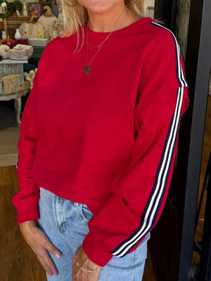 Red sweatshirt with varsity stripe detail on sleeves.