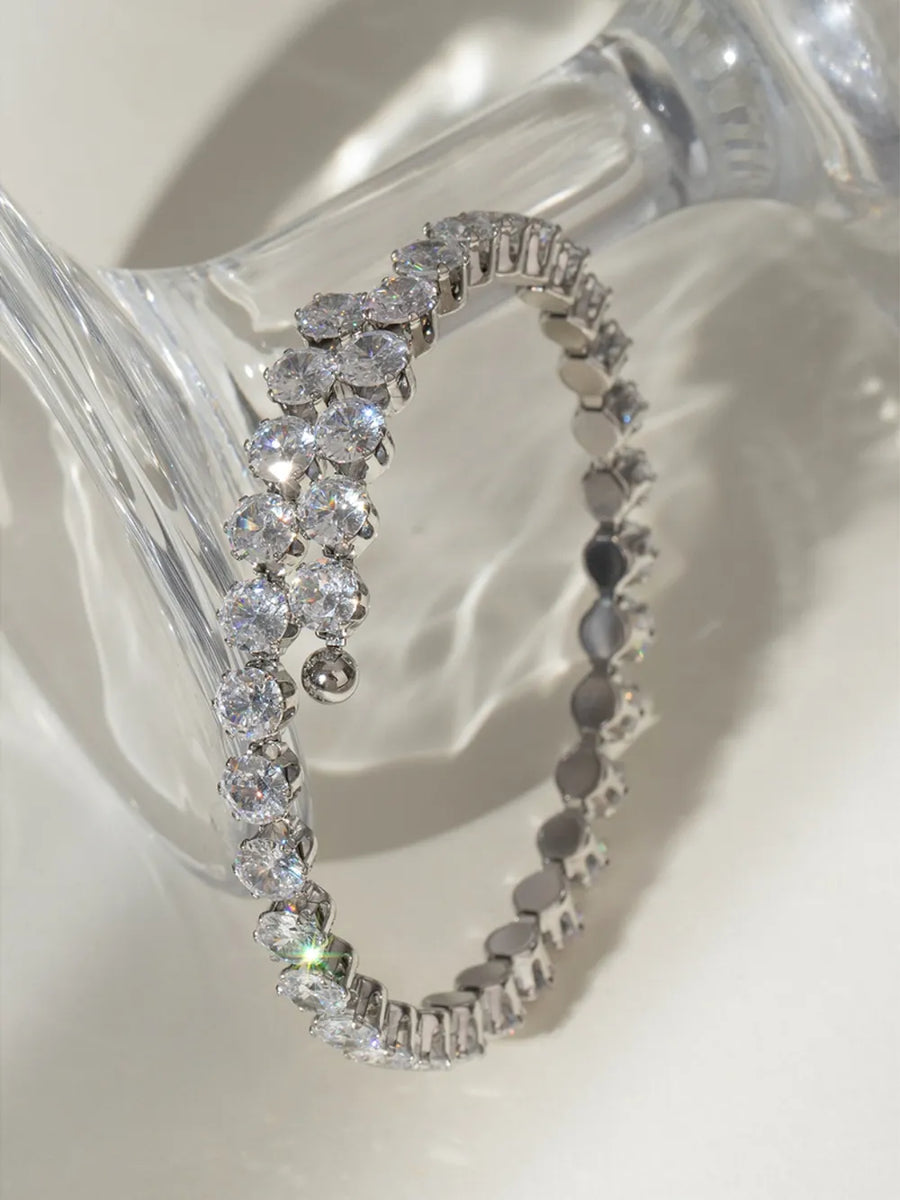 Silver double row pavé bangle bracelet with clear cubic zirconia stones and a dangling charm.