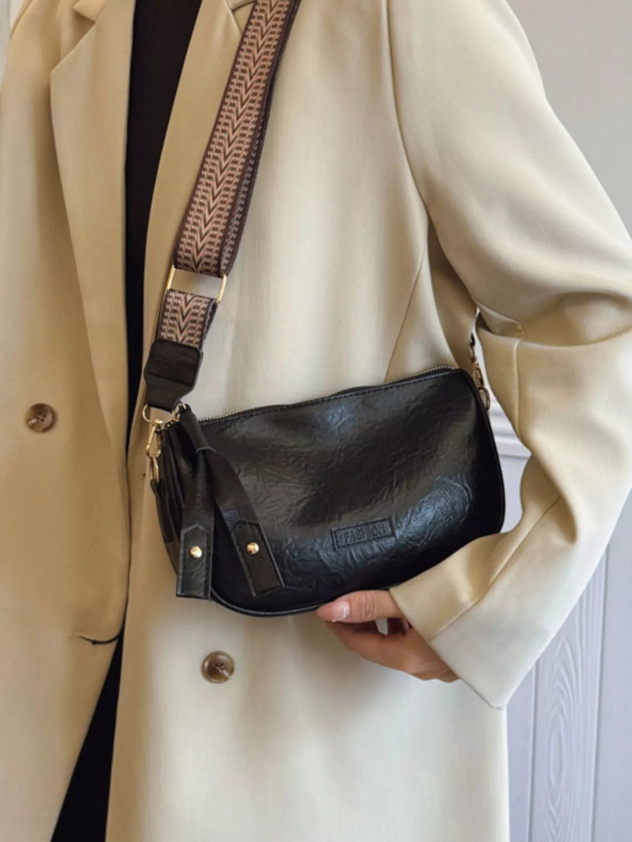 Black crossbody bag with textured faux leather and patterned strap