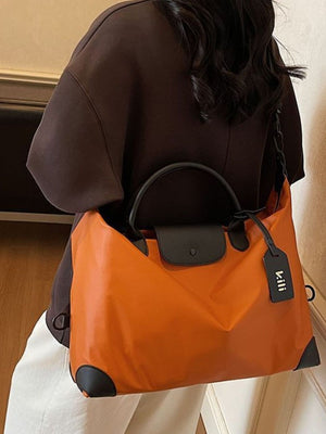 Orange travel duffel bag with black trim and handles, featuring a detachable luggage tag.