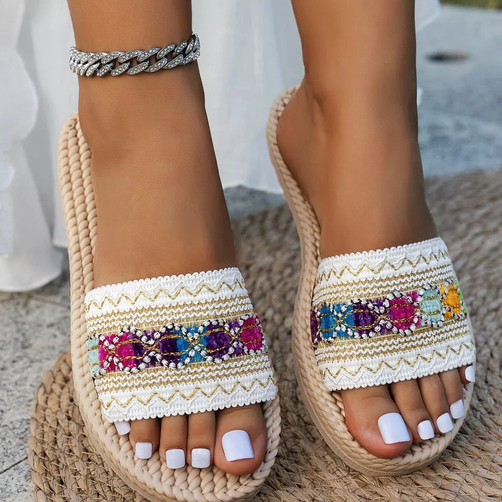 Embossed strap open-toe flat sandals with colorful embroidered detail and braided sole.