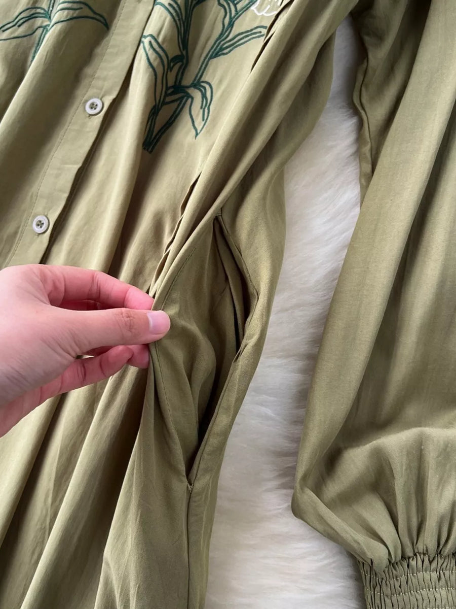 Khaki cotton maxi dress with green floral embroidery and side pockets.
