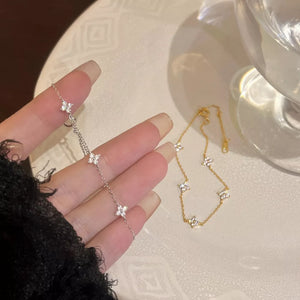 Gold and silver bracelets with clover charms and clear stones.