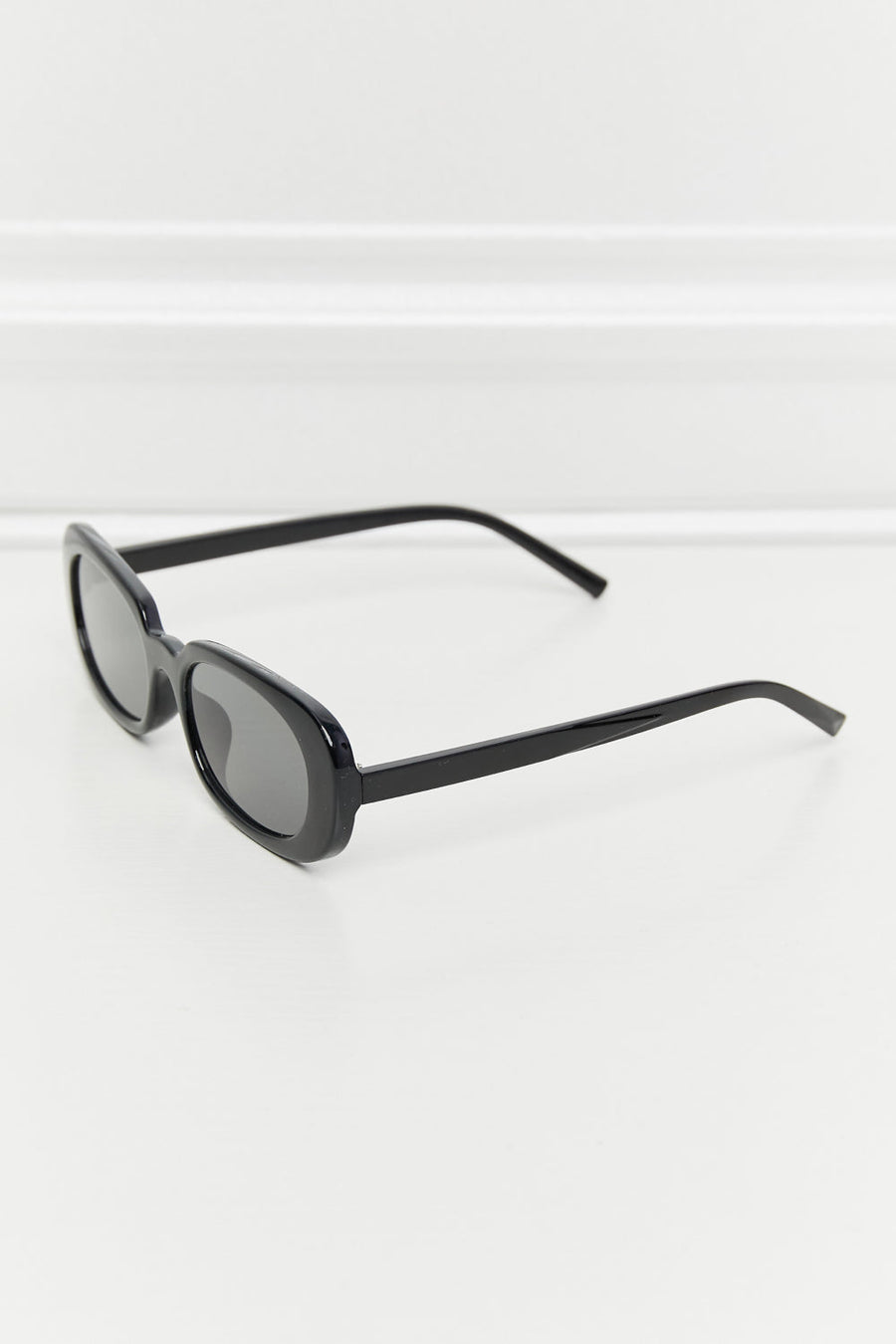 Black oval sunglasses with tortoiseshell sunset lenses and a sleek frame.