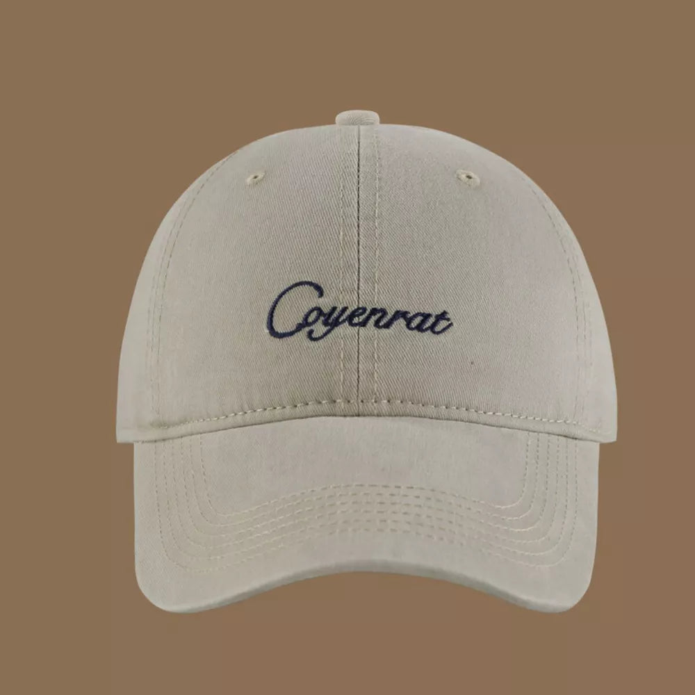 Baseball cap in beige cotton with navy embroidered text and curved brim.