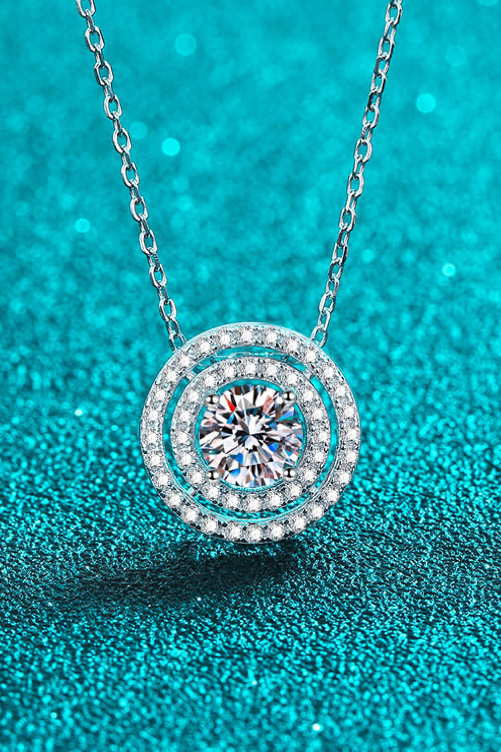 Silver halo diamond pendant necklace with a central sparkling stone.