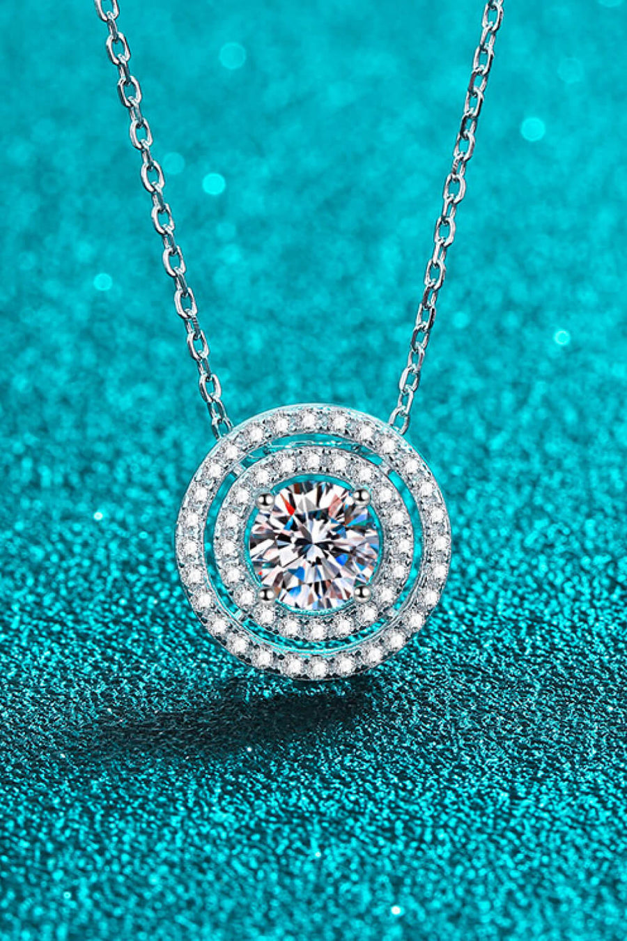 Silver halo diamond pendant necklace with a central sparkling stone.