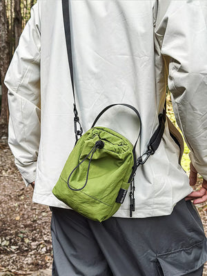 Green mini nylon drawstring shoulder bag with adjustable strap and zipper pulls.