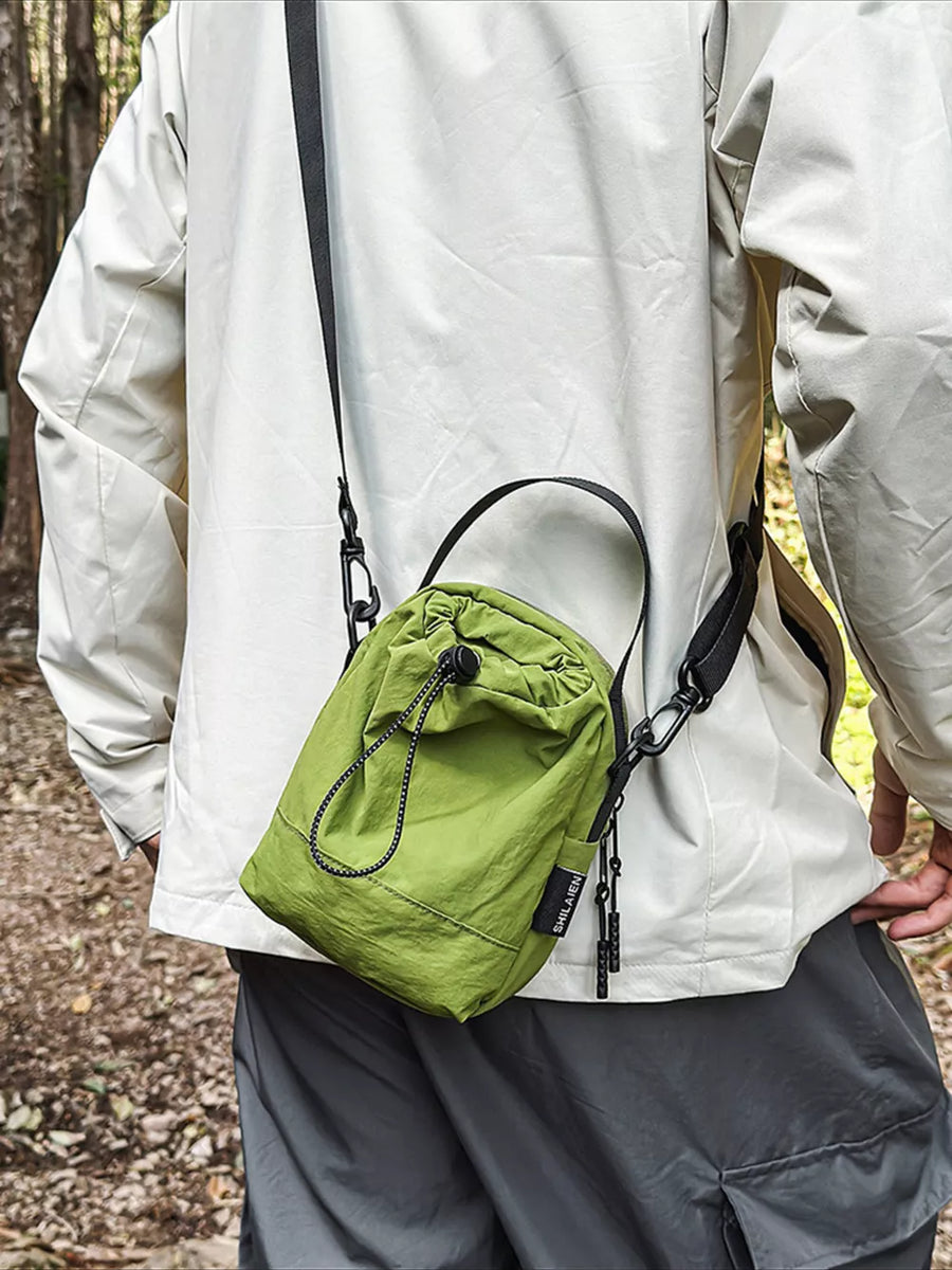 Green mini nylon drawstring shoulder bag with adjustable strap and zipper pulls.