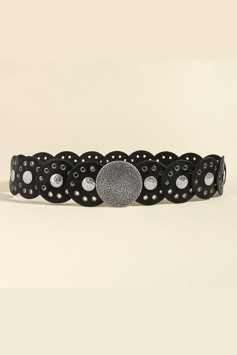 Black faux leather belt with scalloped edge, metal eyelets, and large hammered disc embellishments.
