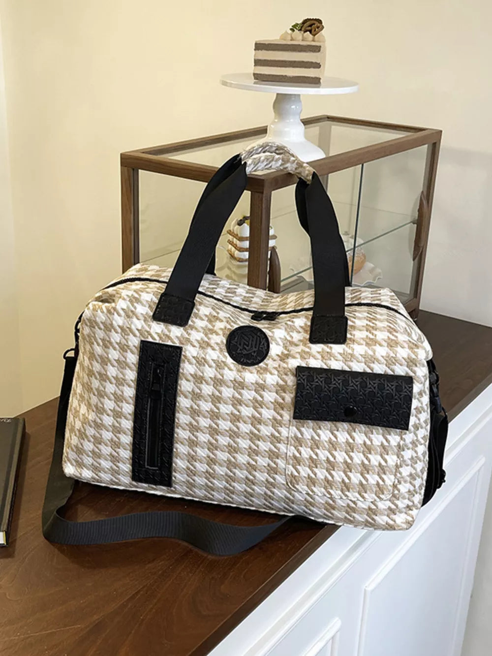 Chic houndstooth duffel bag with black accents and detachable strap