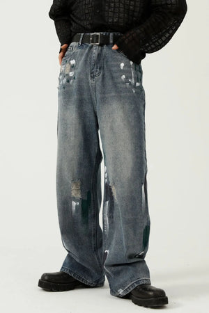 Medium wash baggy jeans with paint splatter details and distressed rips.