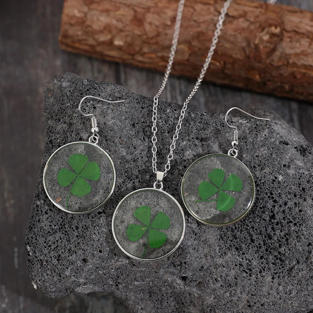 Pressed clover resin jewelry set with green four-leaf clovers in round pendants and earrings.