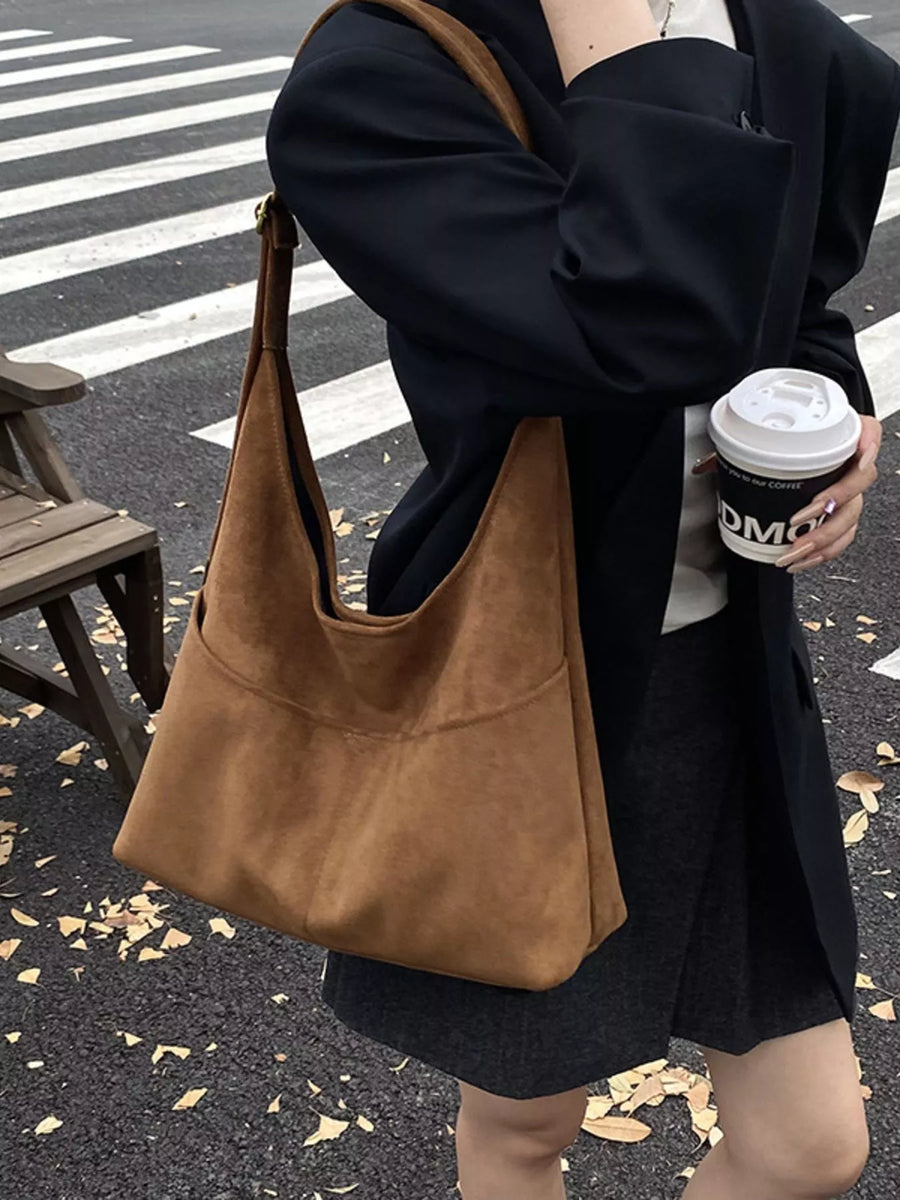 Large brown suede shoulder bag with a slouchy silhouette and exterior pocket.