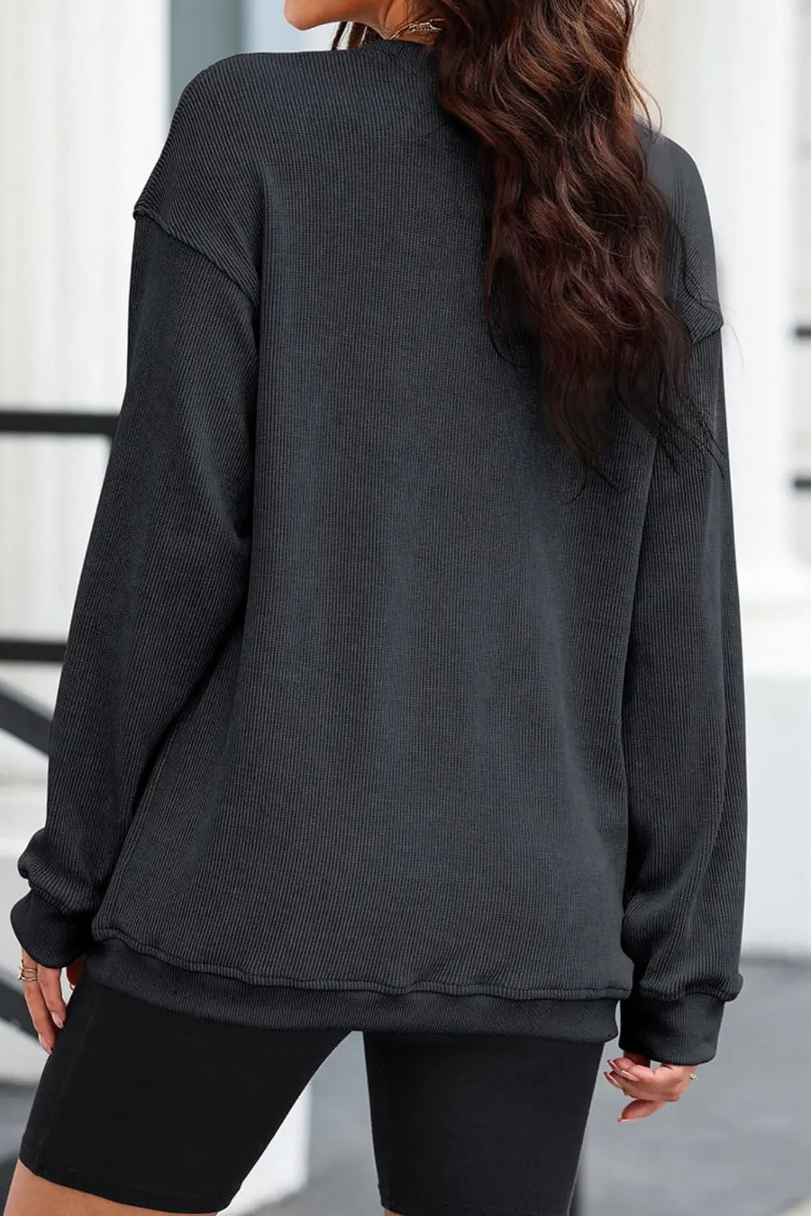 Dark gray ribbed sweatshirt with crewneck and long sleeves, styled with black shorts.
