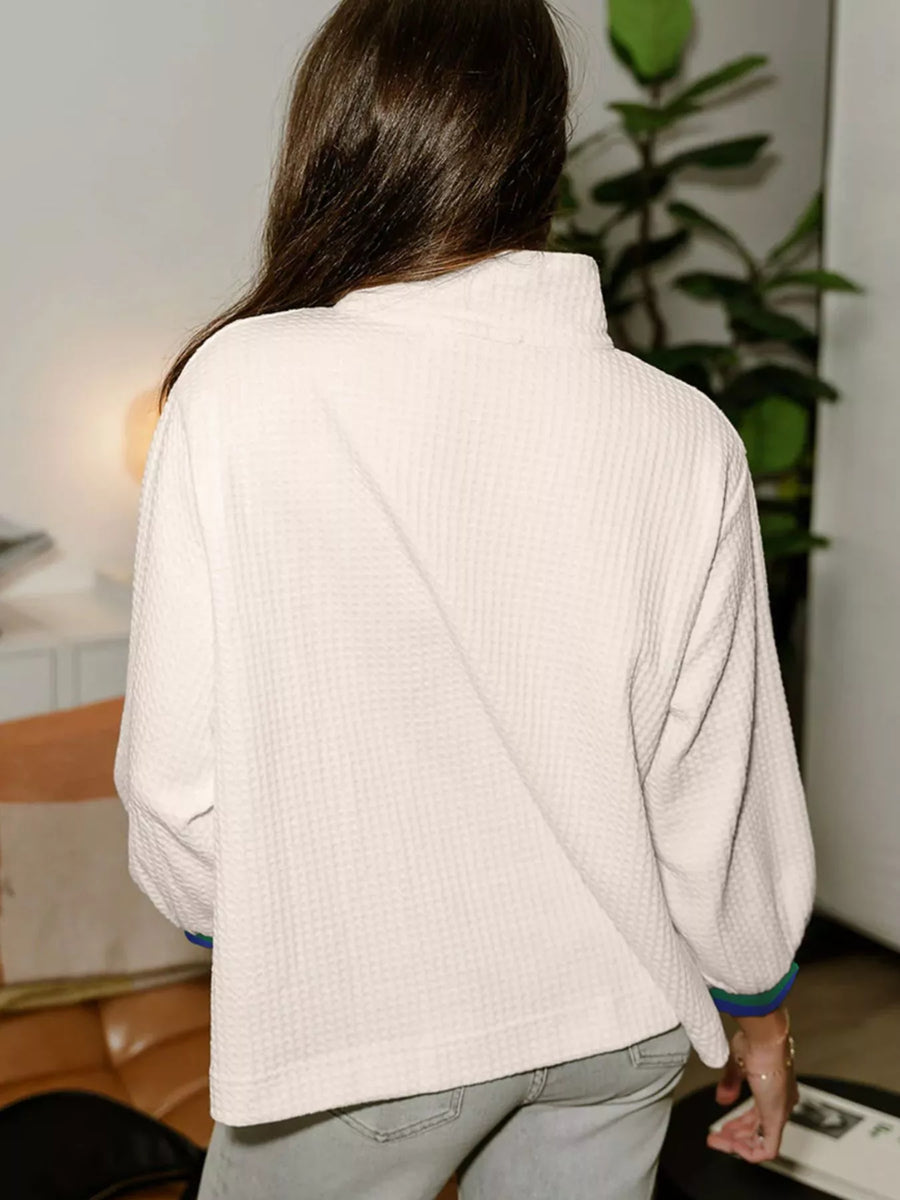 White textured knit half-zip sweatshirt with mock neck and cuffed sleeves.