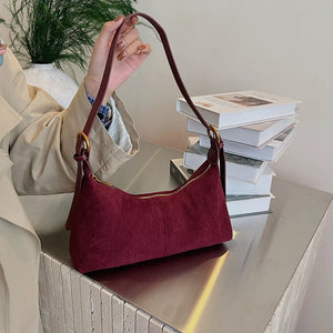 Chic suede crescent shoulder bag in red with adjustable strap and gold hardware.