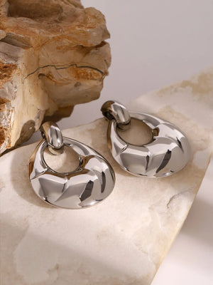 Sculpted silver statement earrings with a polished, abstract design.
