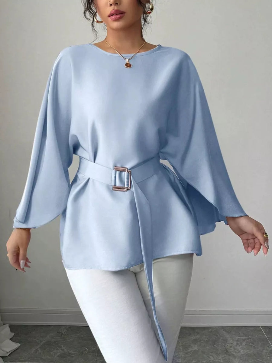 Light blue belted blouse with batwing sleeves and a cinched waist, styled with white pants.