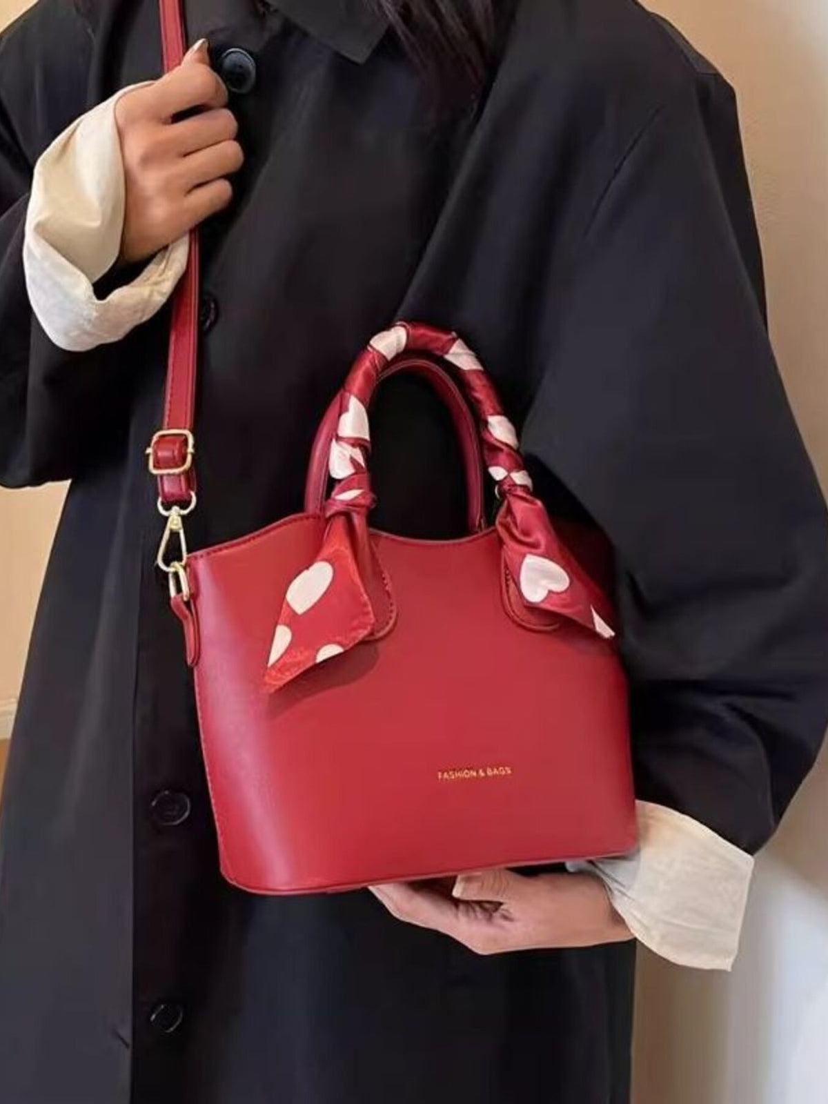 Red pu leather bucket bag with heart print scarf detail and adjustable strap.