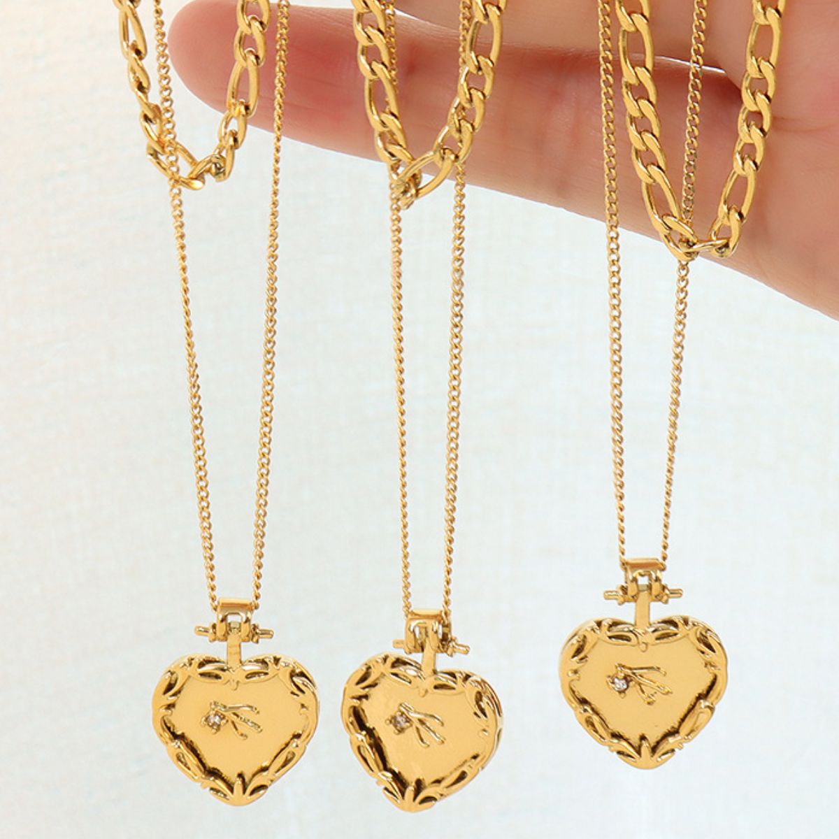 Gold layered heart locket necklaces with delicate chains and a small diamond accent.