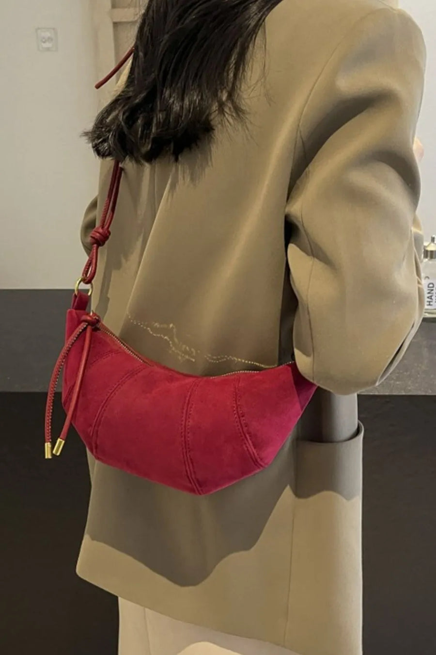 Cerise suede crescent shoulder bag with knot detail and gold hardware