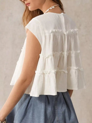 White tiered ruffle blouse with short sleeves and textured fabric.
