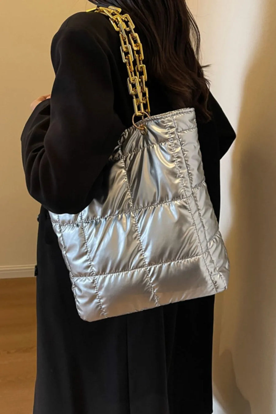 Silver quilted nylon tote bag with a chunky gold chain strap.