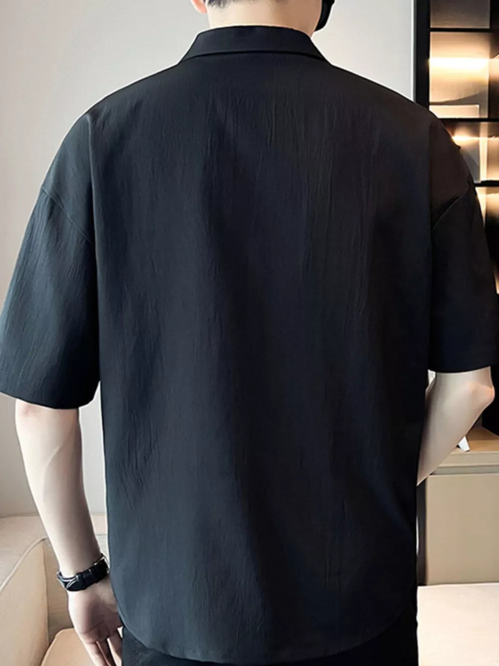 Black cotton polo shirt with short sleeves and a relaxed fit.