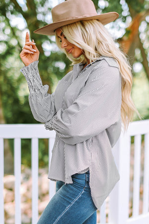 Pinstripe blouse with balloon sleeves and smocked cuffs, styled with jeans.