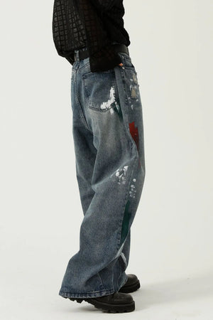Artisan paint-splatter baggy jeans in medium wash denim with red, white, and green paint splatters.