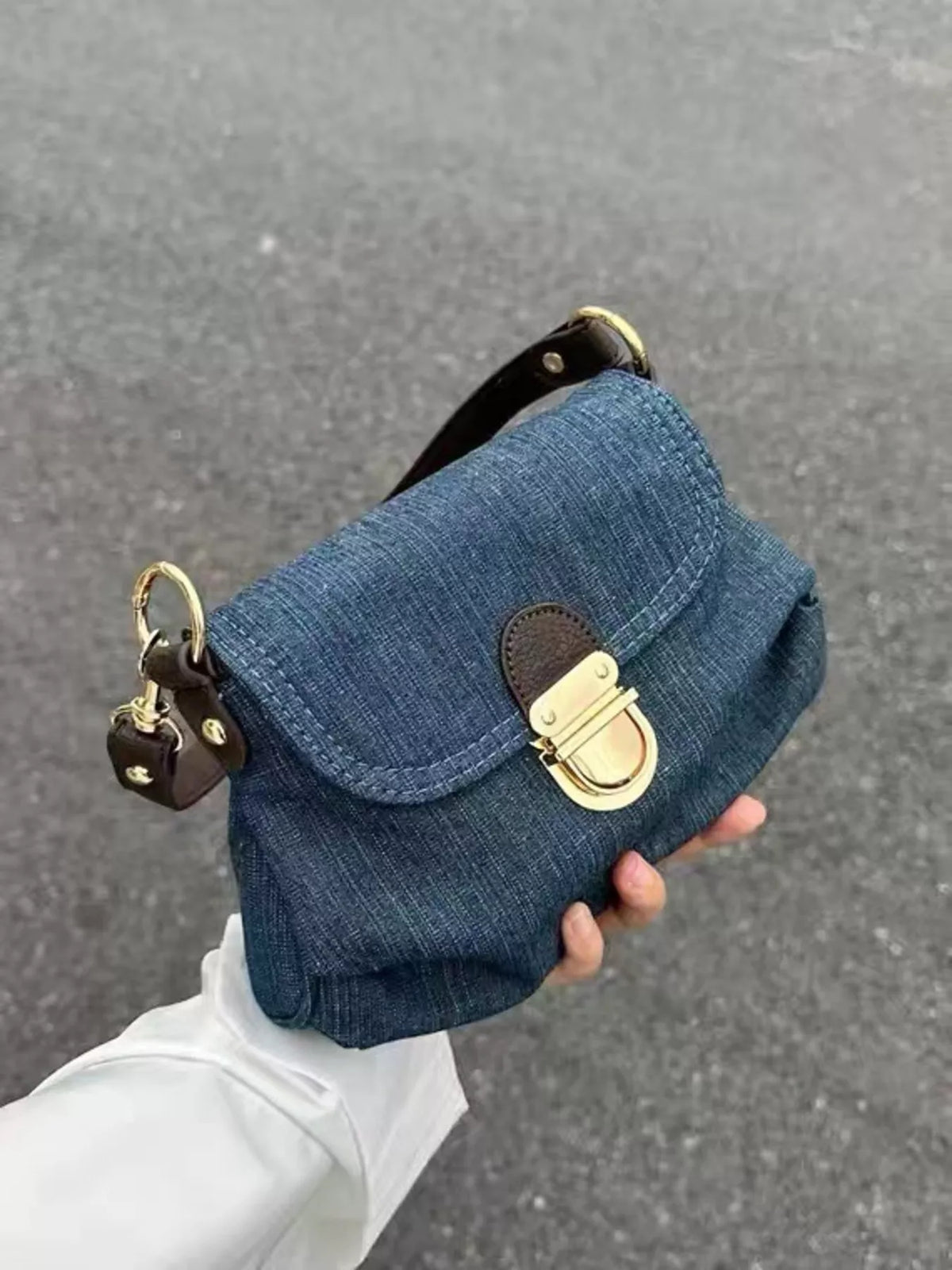 Mini denim shoulder bag in blue with gold hardware and a turn-lock closure.
