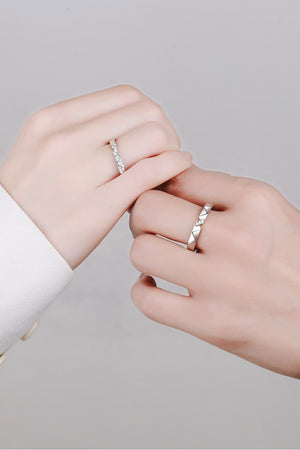 Geometric rhodium pavé ring set with diamond accents on two hands.