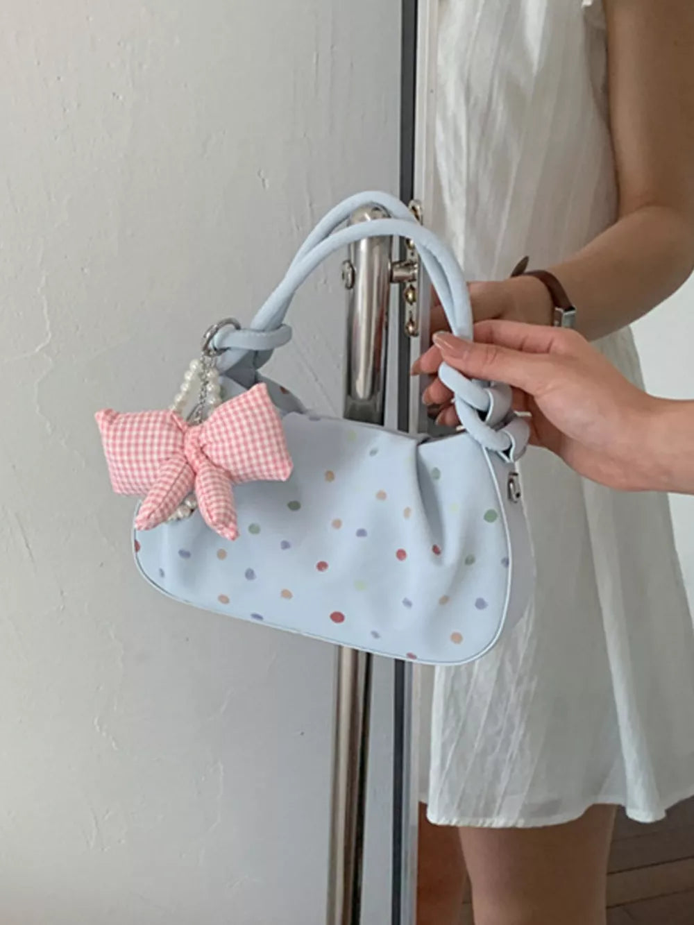 Blue crossbody bag featuring bow charm and polka dot