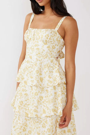 Tiered mini dress with square neckline, spaghetti straps, and yellow floral print on white fabric.