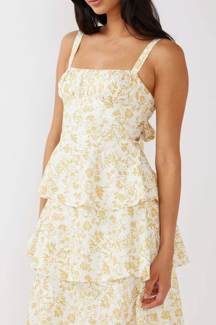 Tiered mini dress with square neckline, spaghetti straps, and yellow floral print on white fabric.