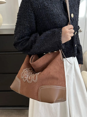 Ochre suede hobo bag with contrast stitching and appliqué detail.