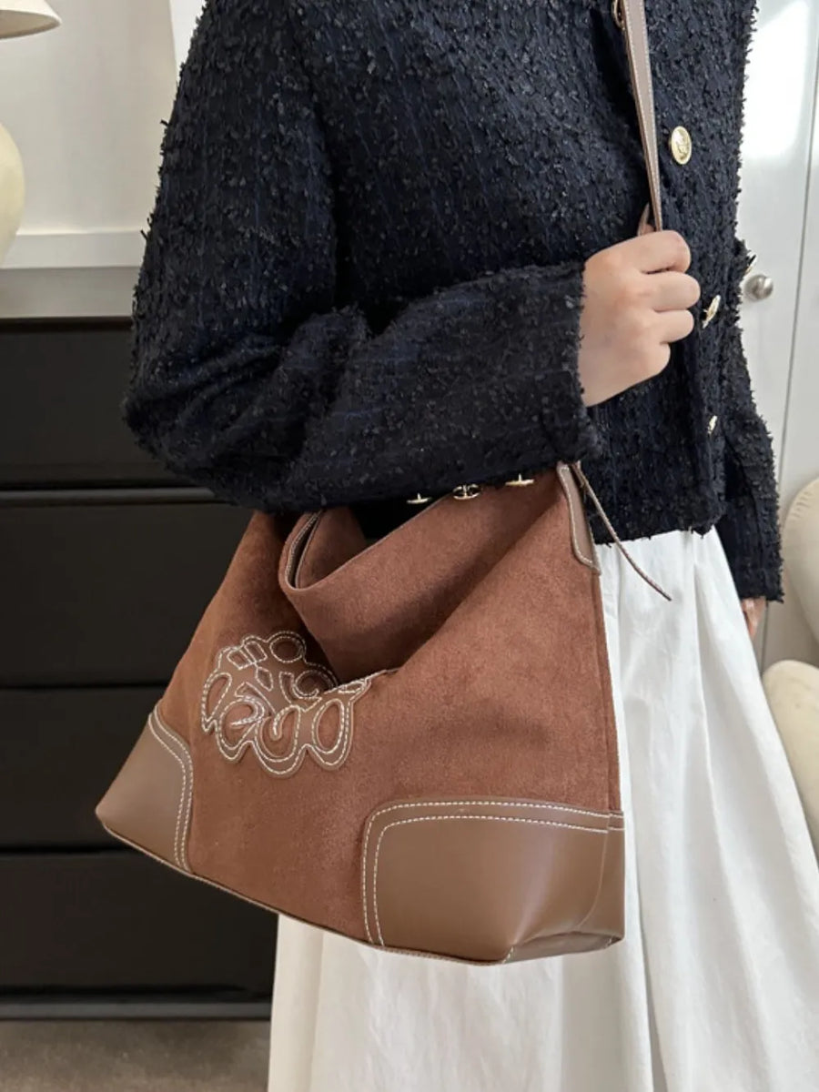 Ochre suede hobo bag with contrast stitching and appliqué detail.