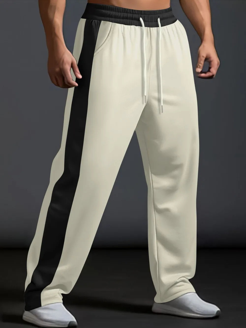 Beige track pants with black side panel detail and white drawstring.