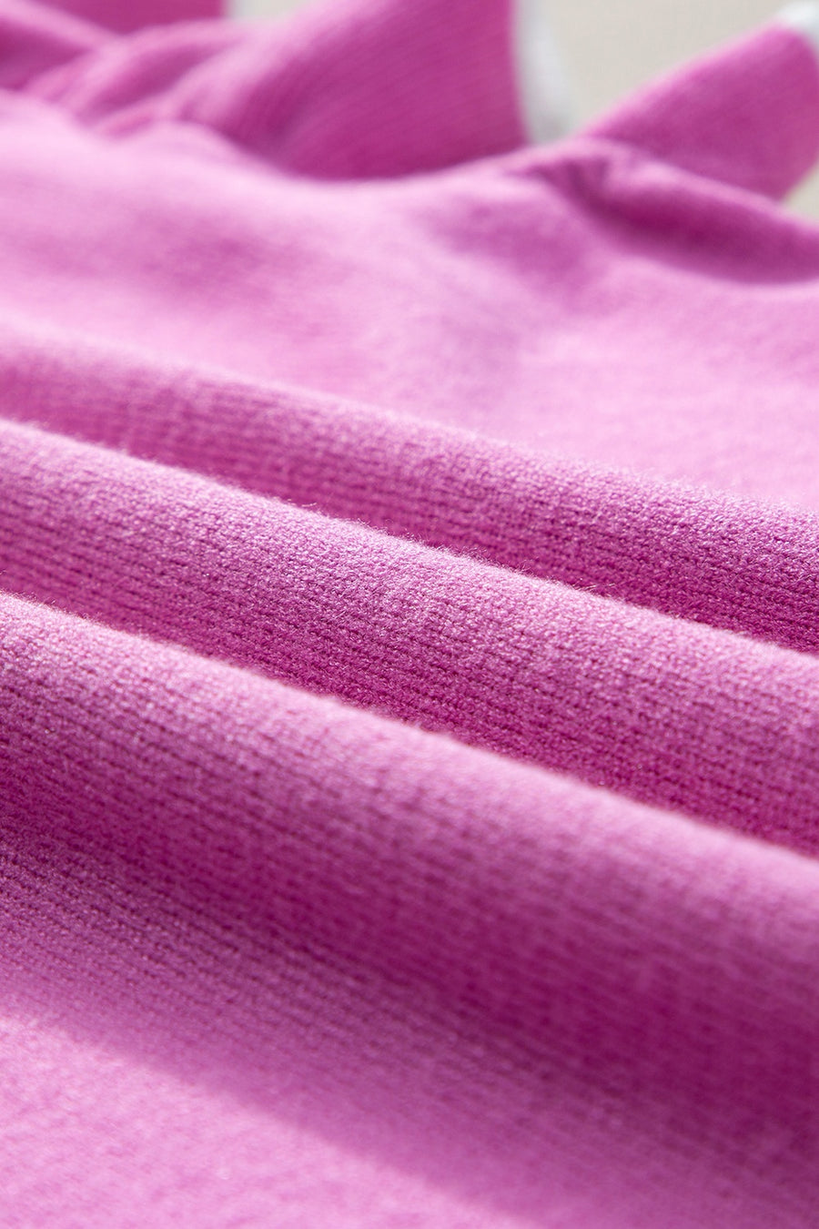 Fuchsia pink knit cardigan with ruffled sleeves and contrast trim detail.