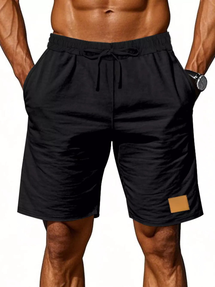 Black chino shorts with drawstring waist and tan patch detail.