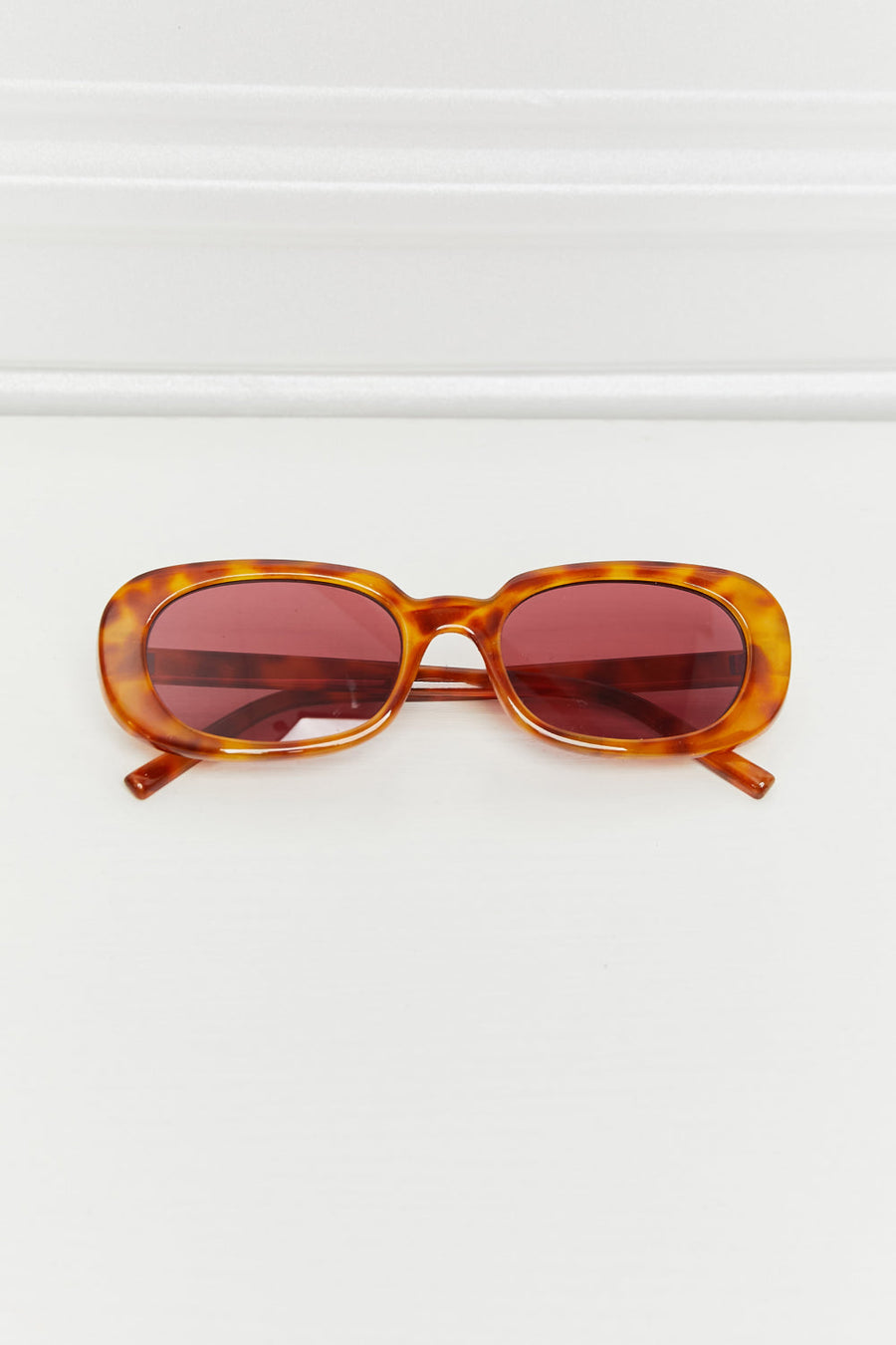 Tortoiseshell oval sunglasses with burgundy sunset lenses and a classic fit.