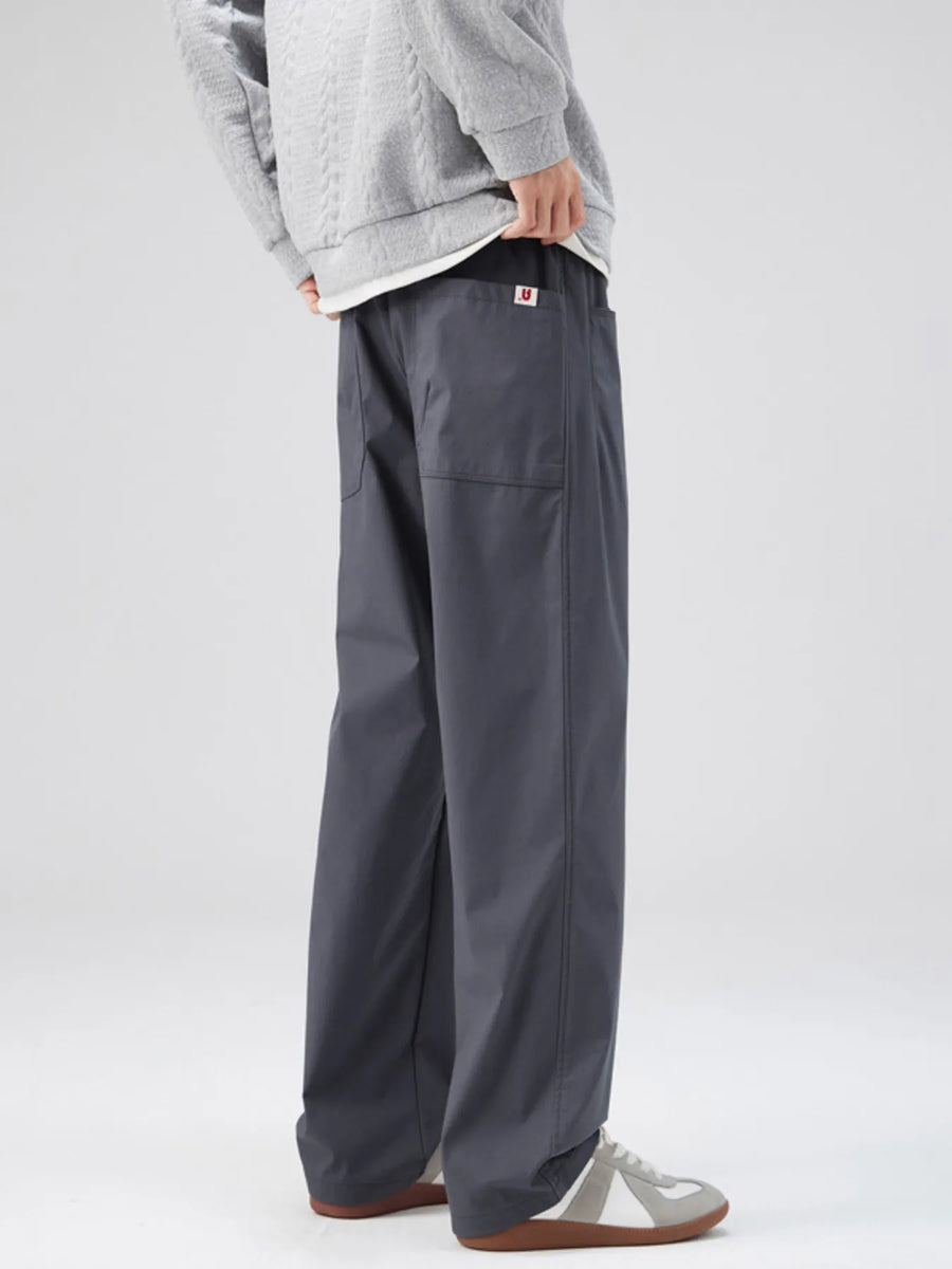 Dark gray casual loose fit pants with patch pockets and a red U logo detail.