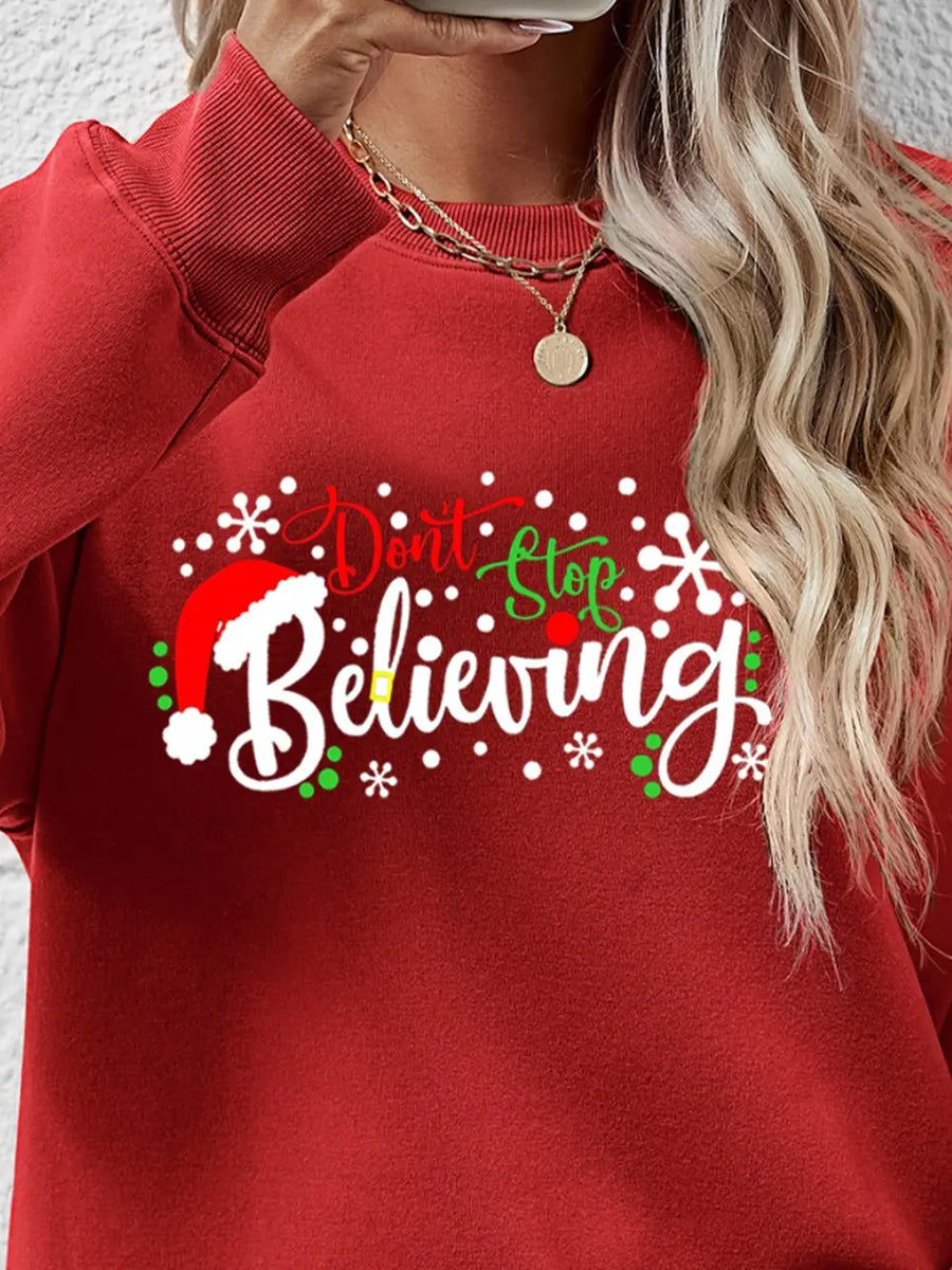 Red crew neck sweater with "Don't Stop Believing" graphic and Santa hat detail.