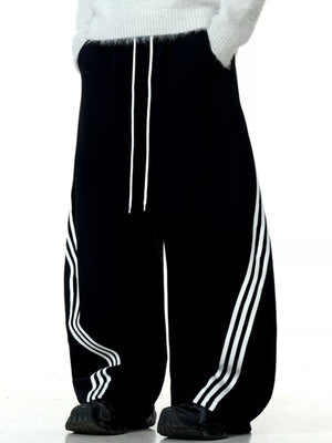 Men's black wide-leg sweatpants with white side stripes and drawstring waist.